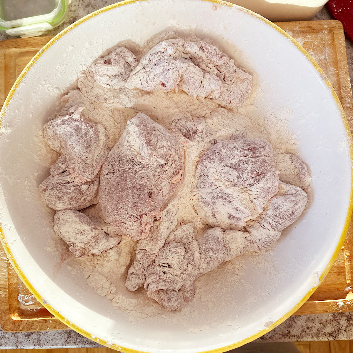 Pheasant pieces in large bowl dusted with flour.
