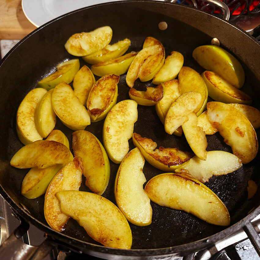 Browned, sautéed apple slices in large skillet.