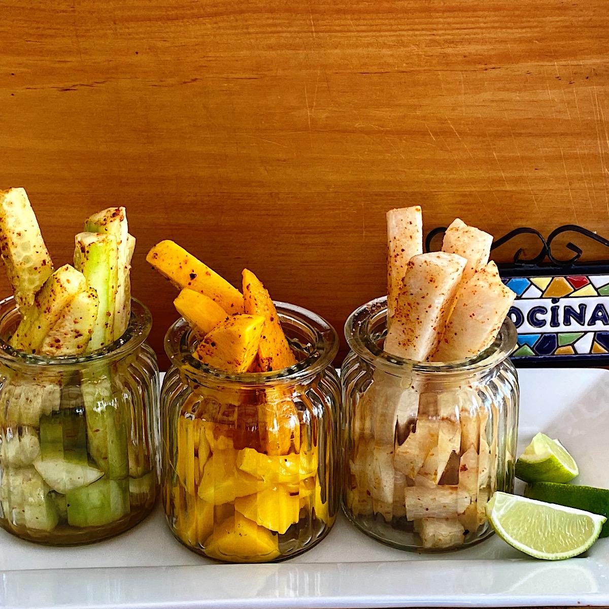 Fruit planks in glass jars sprinkled with chile lime seasoning as Mexican street food