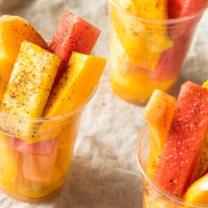 Fruit wedges in a plastic cup sprinkled with chile lime salt.
