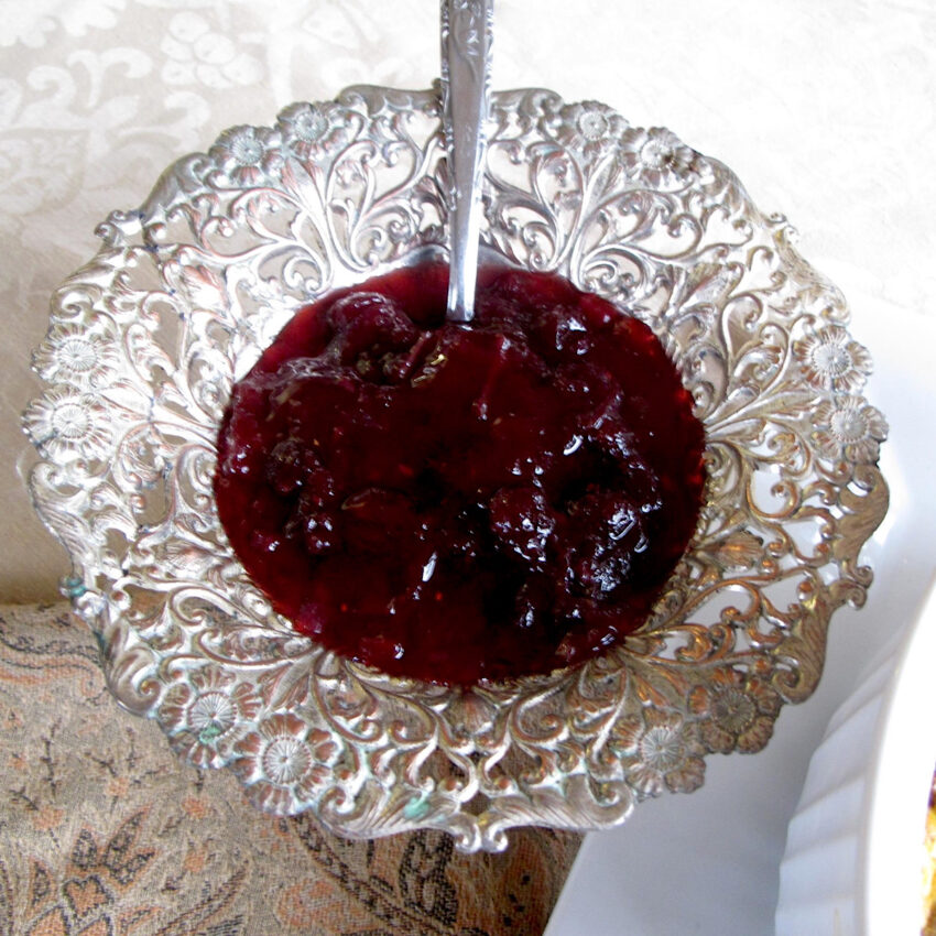 Cranberry chutney in a silver bowl with a spoon.