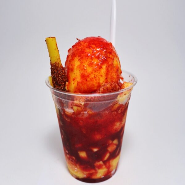 Chamoy fruit sauce as a condiment  over Mexican street food in a plastic cup.