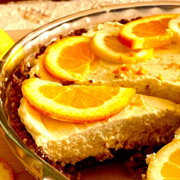 Close up of a slice of faux Meyer lemon pie topped with orange slices.
