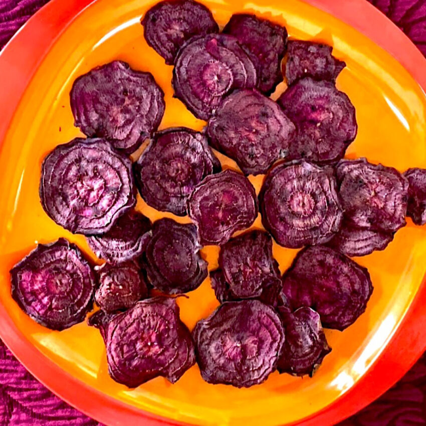 Beet chips dried in a dehydrator, on an orange plate.