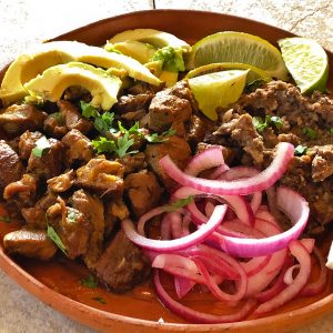 Plate of carnitas with pickled onions and avocado