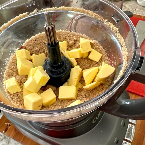 Food processor with almond flour, sugar and butter ready to mix into crumble topping.