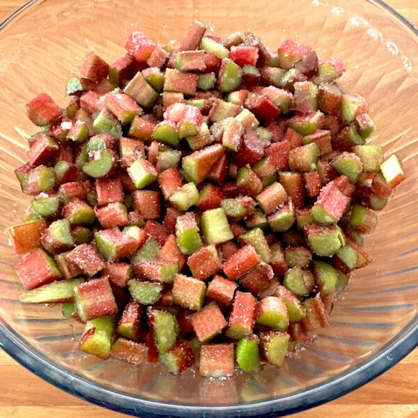 Bowl of rhubarb cut into small pieces and sprinkled with sugar.
