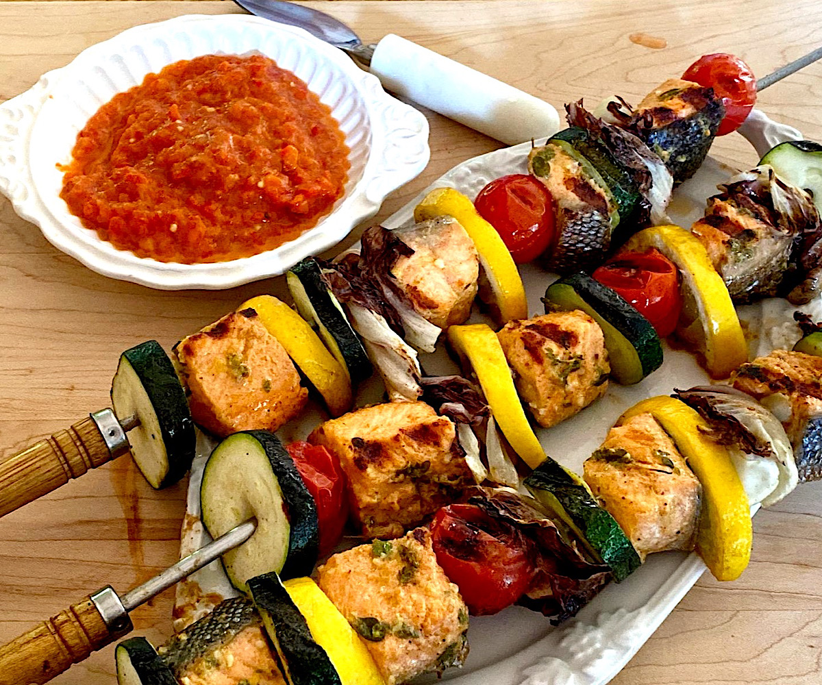 Salmon vegetable kebabs with a side dish of red pepper dipping sauce.
