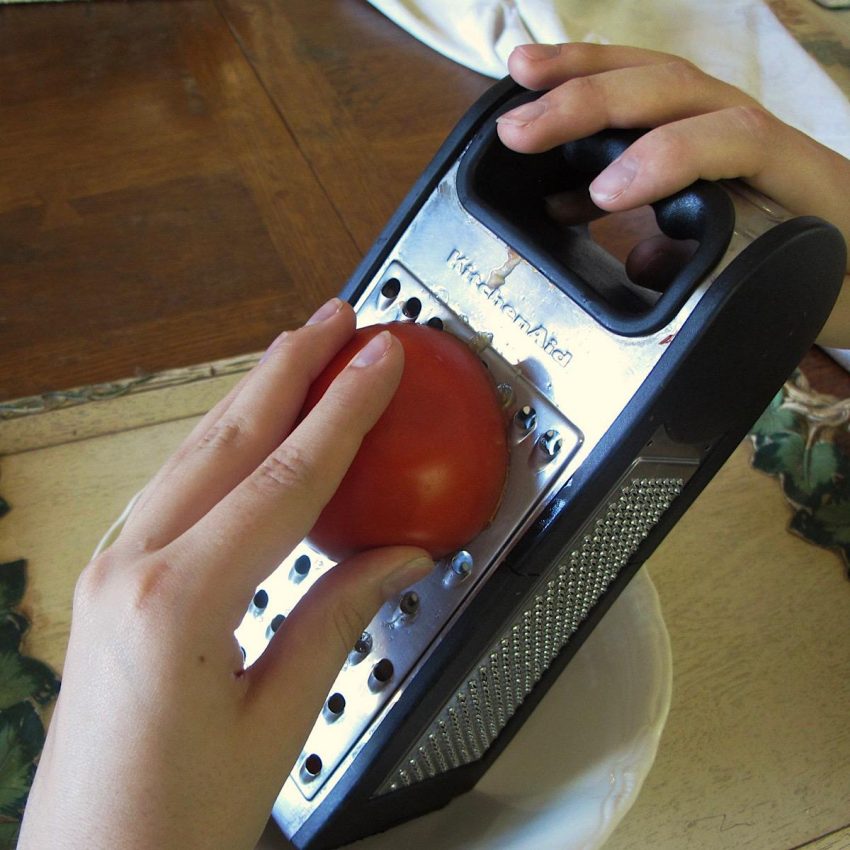 Using box grater to grate tomatoes for Andalusian Tomato Bread