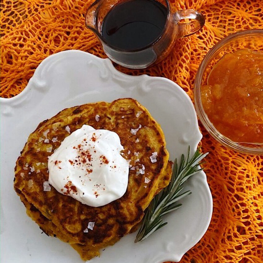 Pumpkin pancakes with a dollop of sour cream on top and a side of maple syrup and orange marmalade.