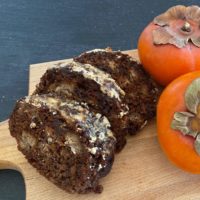 3 slices of persimmon steamed pudding on a board with persimmons
