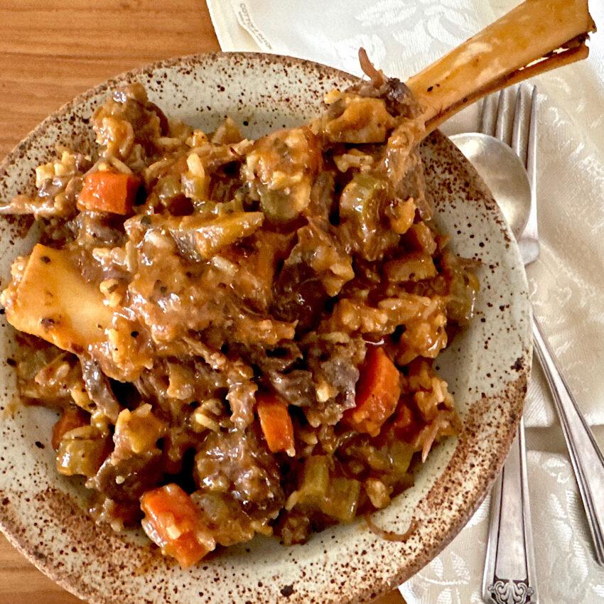 Bowl of osso buco with lamb shanks, carrots and broth.