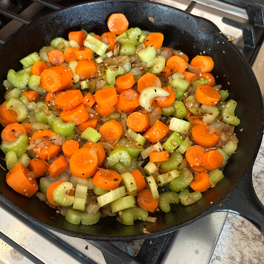 Carrots, celery and onions being cooked in skillet in preparation for osso buco.
