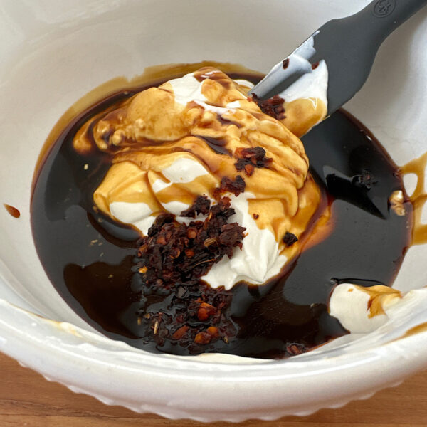 Bowl of sour cream, pomegranate molasses, and chile  paste for the kimchi pancake topping.