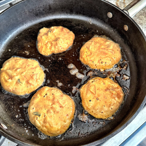 5 kimchi pancakes in a skillet, each about 3 inches and not touching.