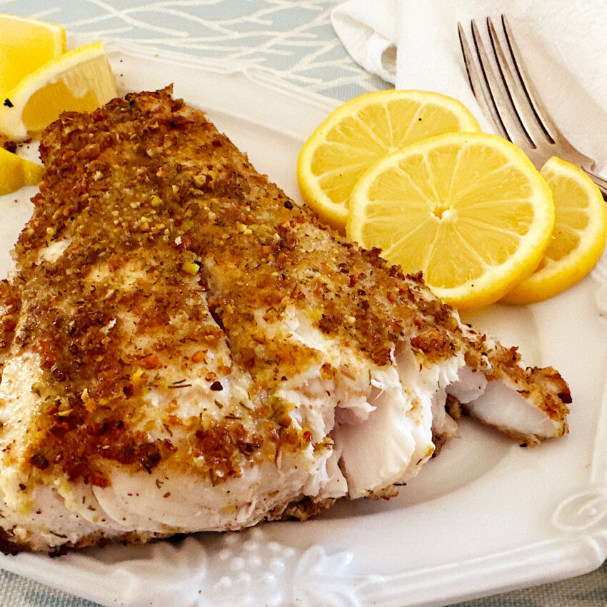 Red snapper filet sautéed  with a pistachio crust and a side of lemon slices.