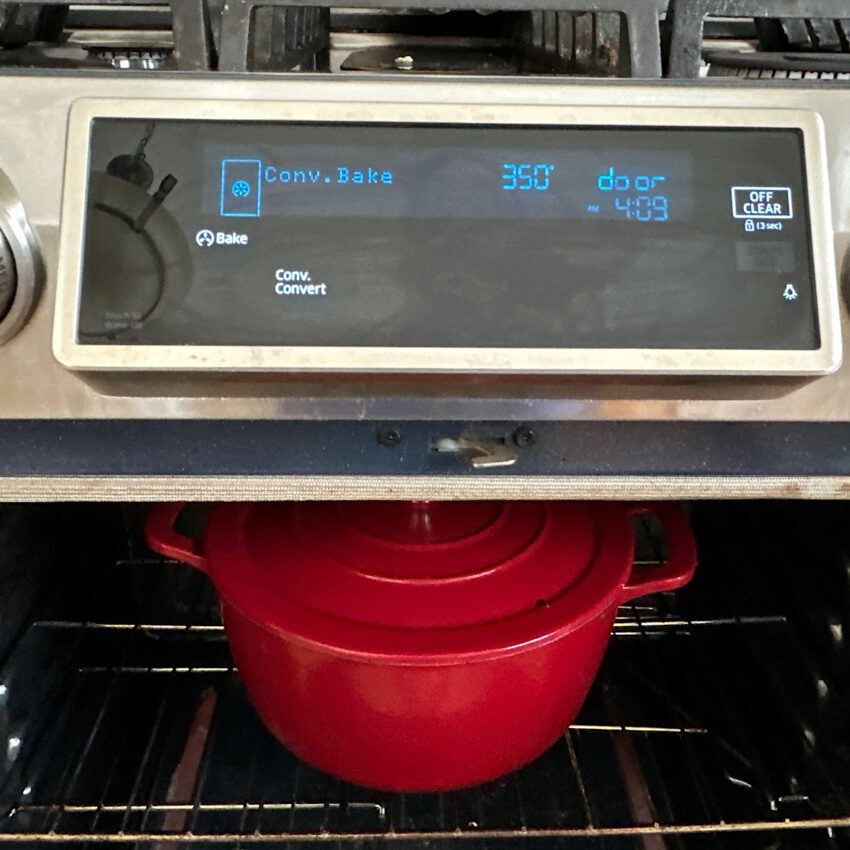 Covered dutch oven with stew inside, cooking in oven set at 350 degrees.