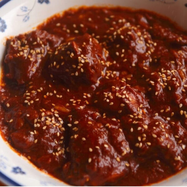 Mole rojo sauce covering chicken pieces in a bowl