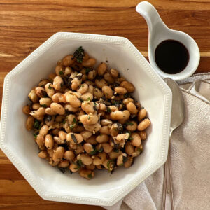 Bowl of dried cannellini beans with side of balsamic vinegar cooked in Instant pot.