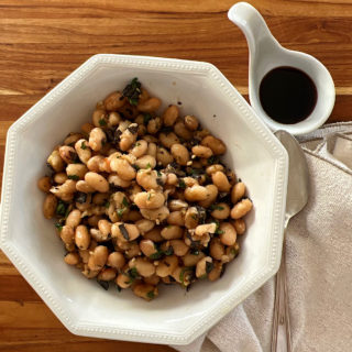 Bowl of dried cannellini beans with side of balsamic vinegar cooked in Instant pot.
