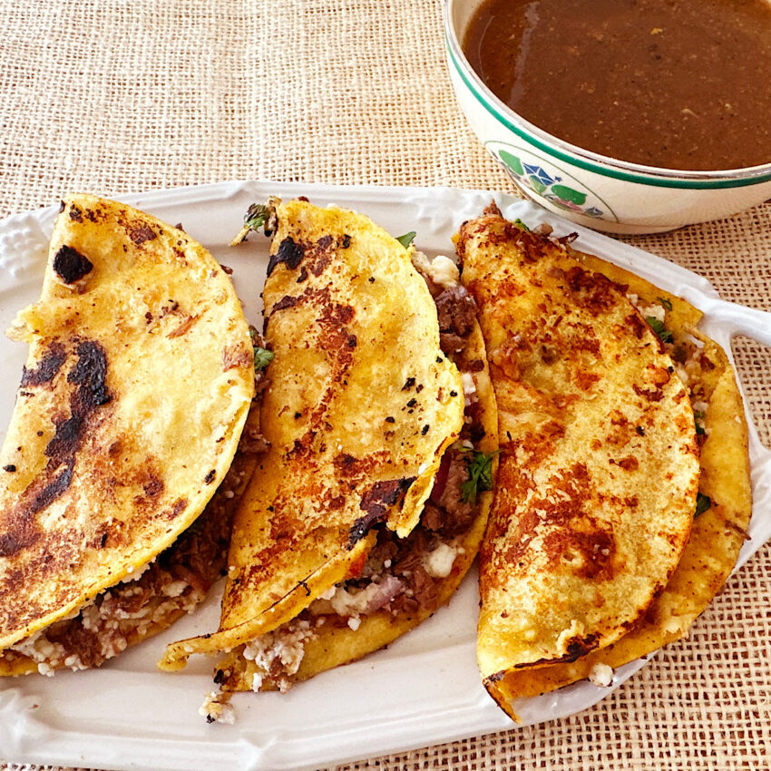 3 beef birria quesotacos with a side of beef birria consommé.