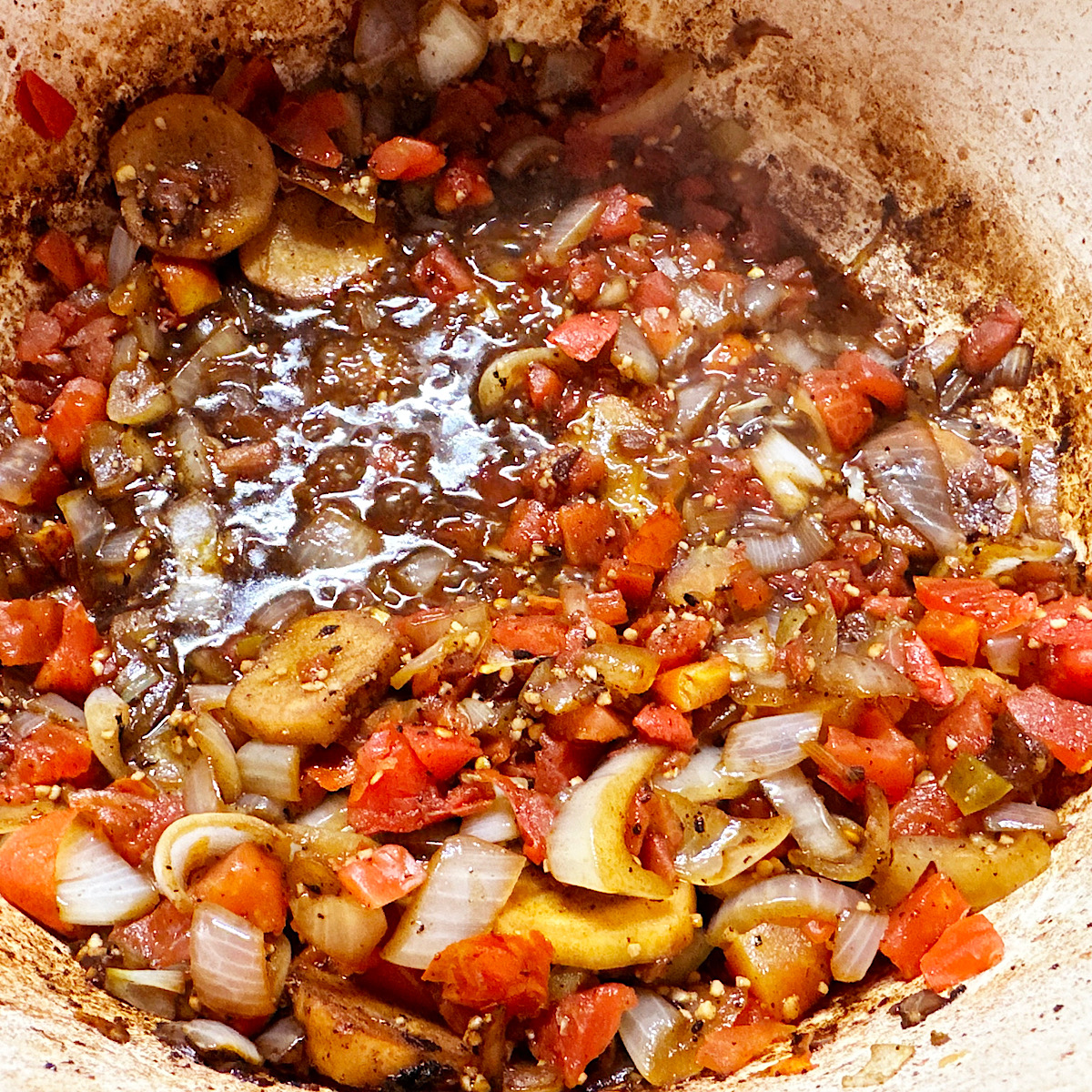 Onions, tomatoes, spices and ginger simmering in a dutch oven.