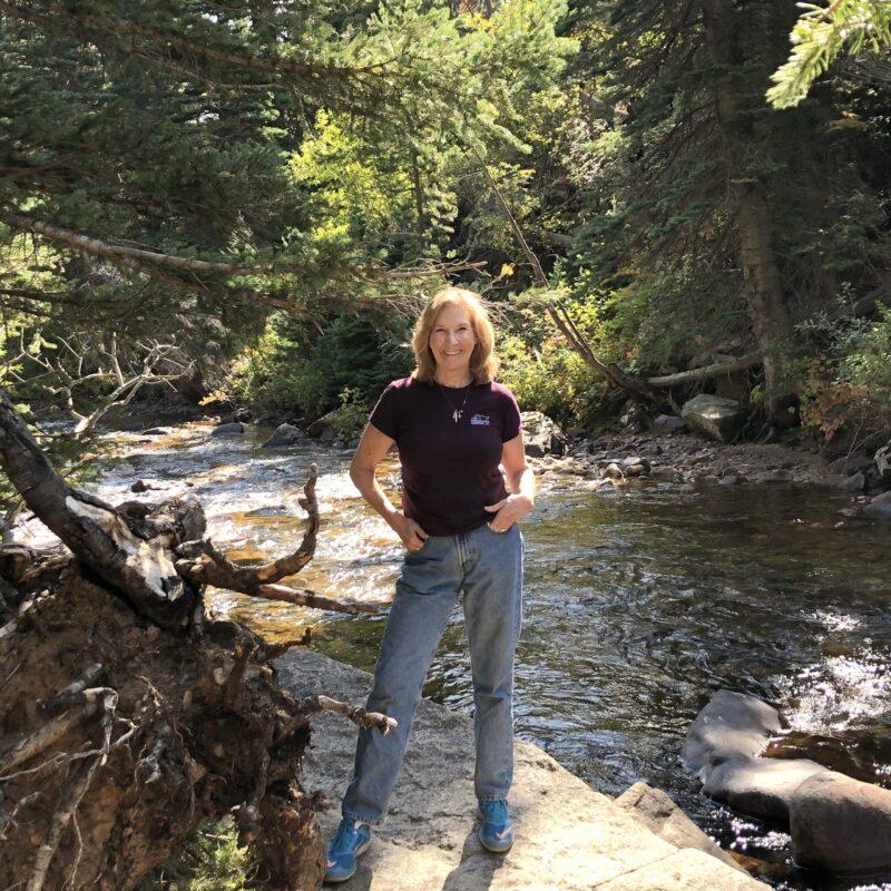 The autho by a stream on a hike in Colorado