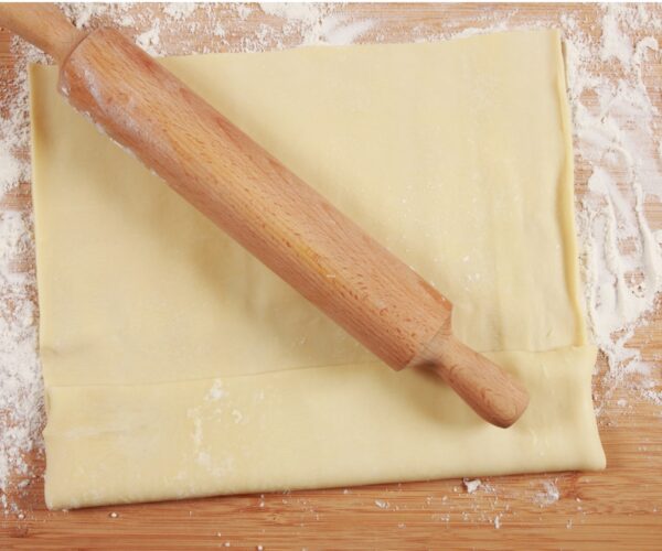 Store bought pastry dough being rolled out for a square tart.