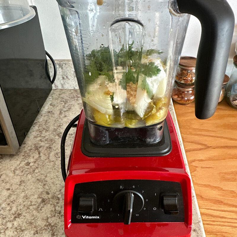 Blender with tomatillo verde ingredients in it.