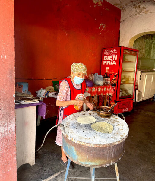 Woman in Oaxaca making tortillas on a large burner used as a comal.