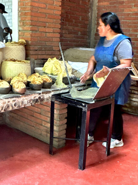 Oaxacan restaurant worker making tortillas in a cast iron press.