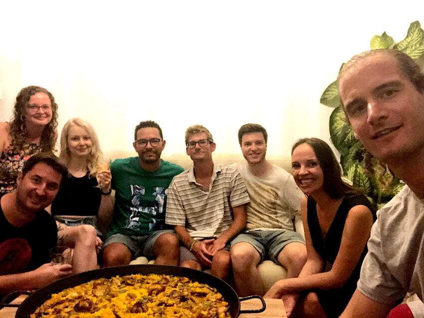 Group of young people with paella in front of them.