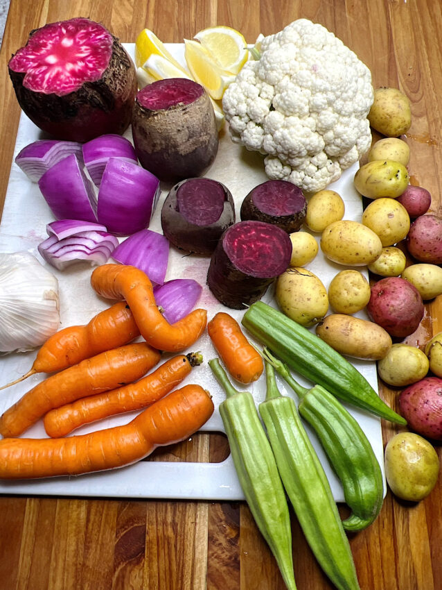 A variety of root vegetables on cutting board, including carrots, beets, cauliflower, and potatoes.