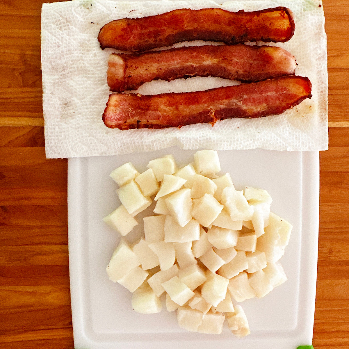 3 slices bacon and chopped cod on cutting board.