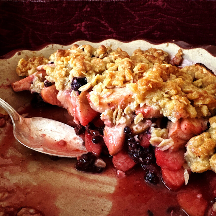 Side view of apple blackberry crumble in a pie plate showing filling to topping ratio. 