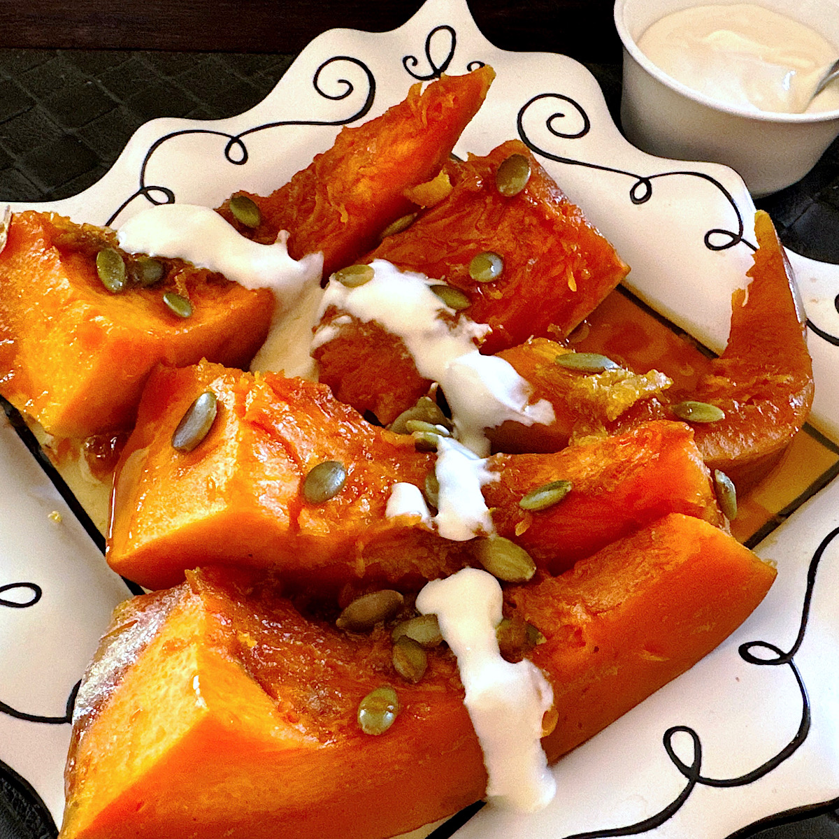Candied pumpkin on a white plate with Mexican creama drizzled over it.