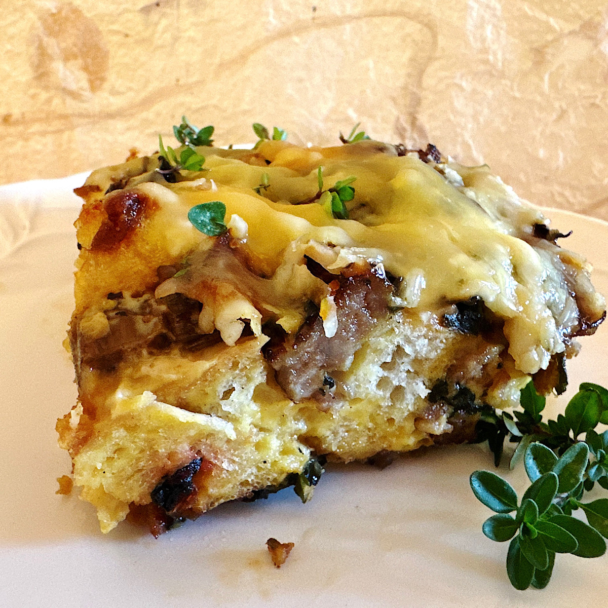 Serving of egg casserole (strata) with sausage and swiss chard on a plate.