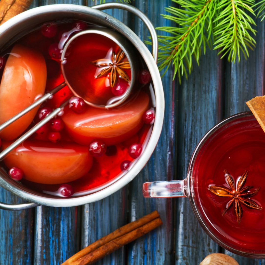 Pot of big batch cranberry apple tea with cup of tea on the side.