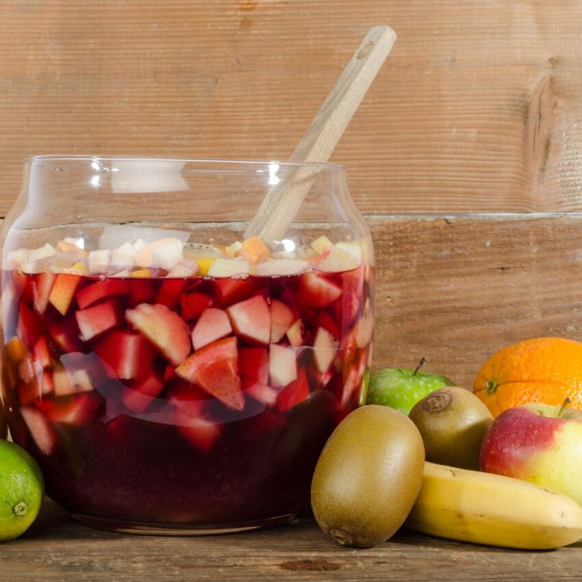 Guatamalan fruit punch in a punch bowl with associated fruit on the table beside the punch bowl.