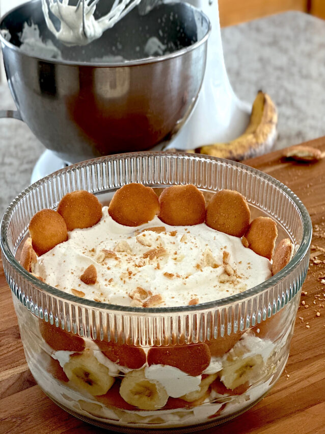 Southern banana pudding in glass bowl with vanilla wafers surrounding the whipped cream.