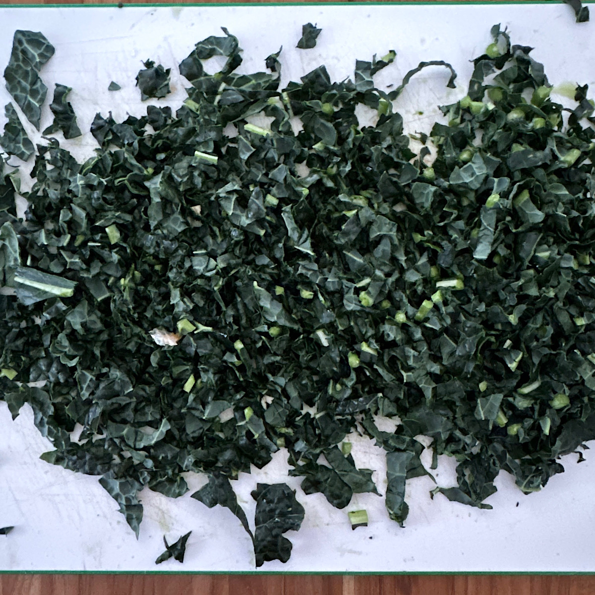 Finely chopped kale on white cutting board.