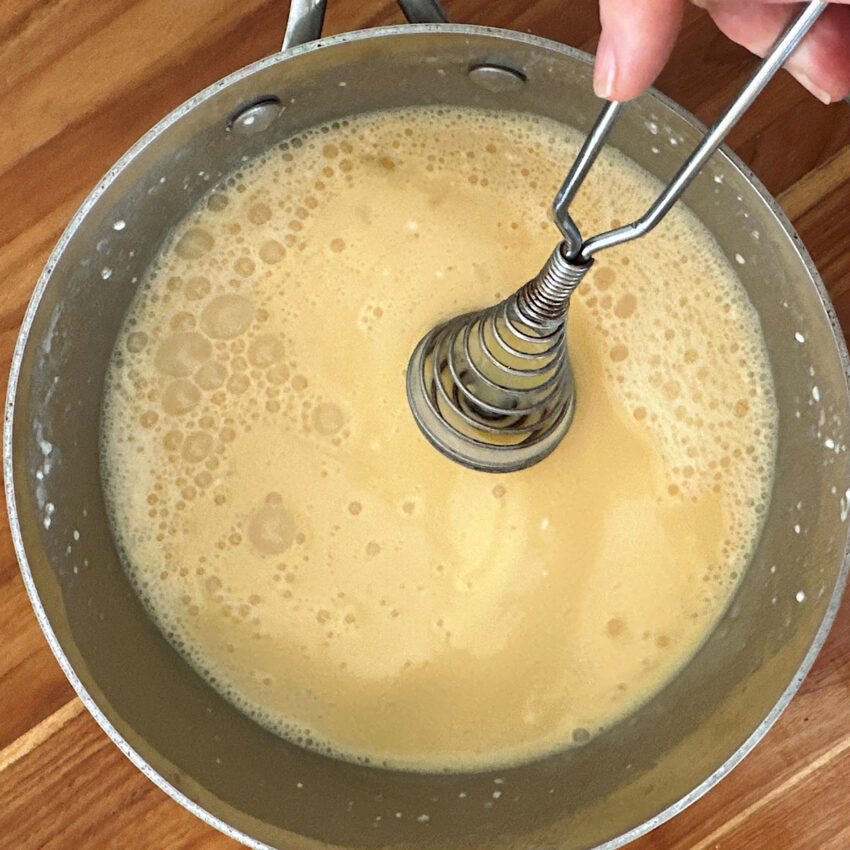 Saucepan with pudding ingredients being whisked together.