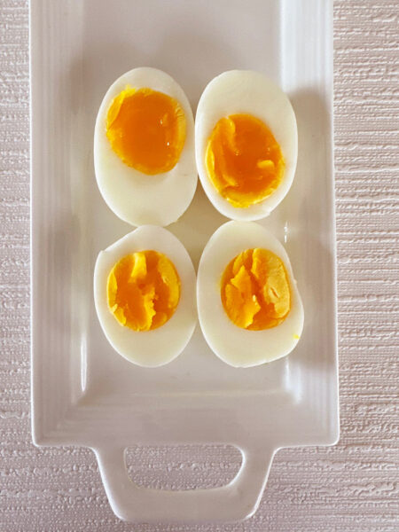 Example of soft-boiled eggs (top) and hard boiled eggs (bottom) on a white platter.