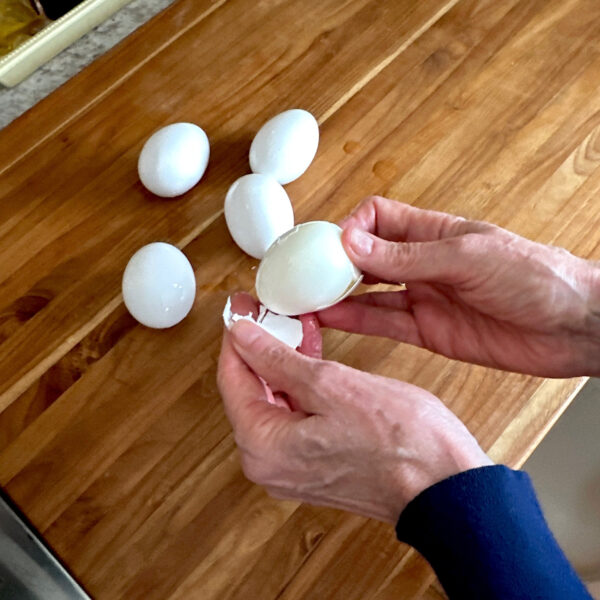 Hands showing the ease of peeling a soft-boiled egg that has gone through an ice bath.