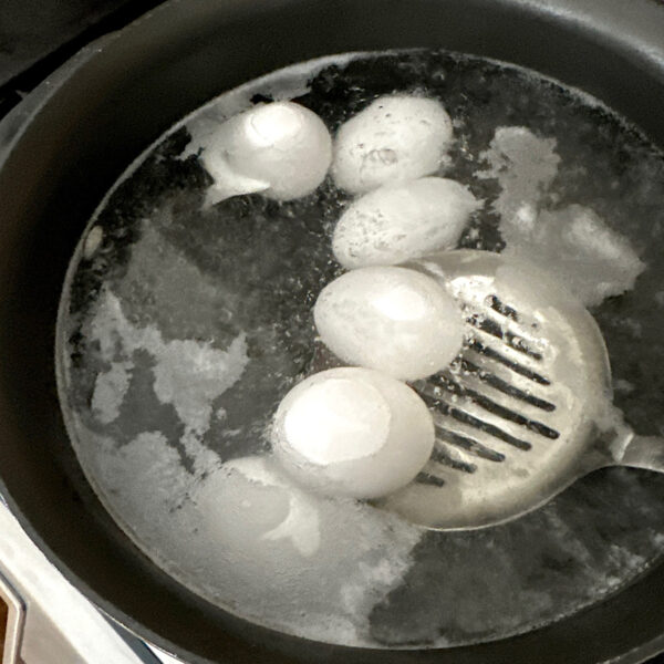 Use of a stainless steel spatula to lower eggs into pot of boiling water.