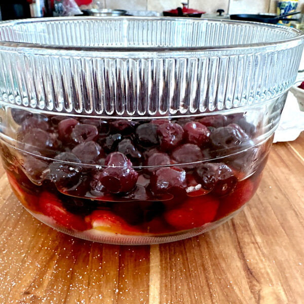 Blueberries in a glass bowl macerating in sugar.