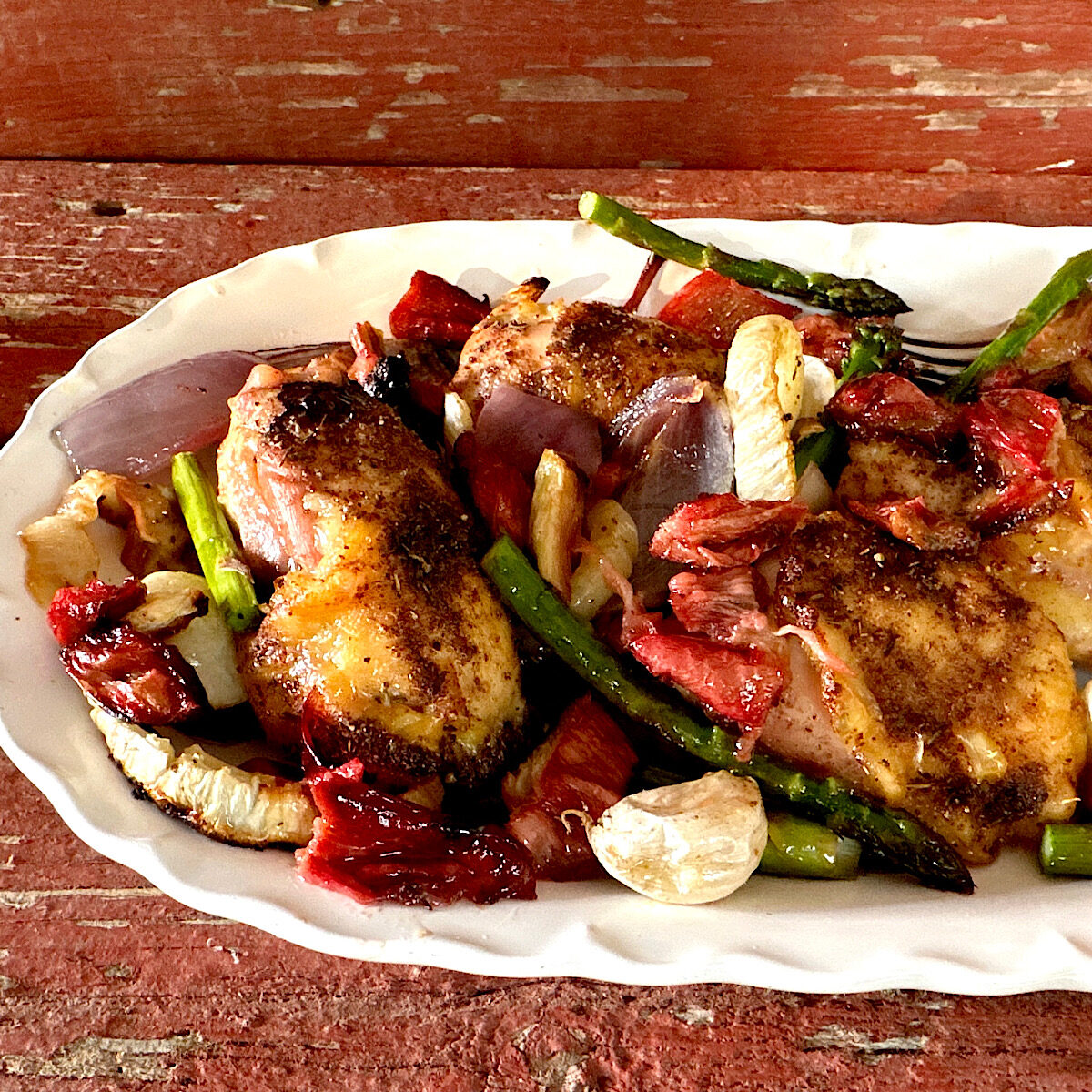 Sheet pan chicken, rhubarb and asparagus on white plate.