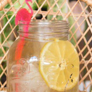Mason jar with chamomile iced tea and slice of lemon and flamingo garnish.