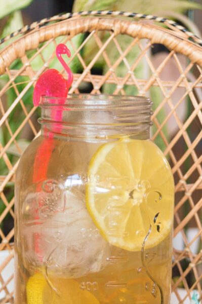 Mason jar with chamomile iced tea and slice of lemon and flamingo garnish.