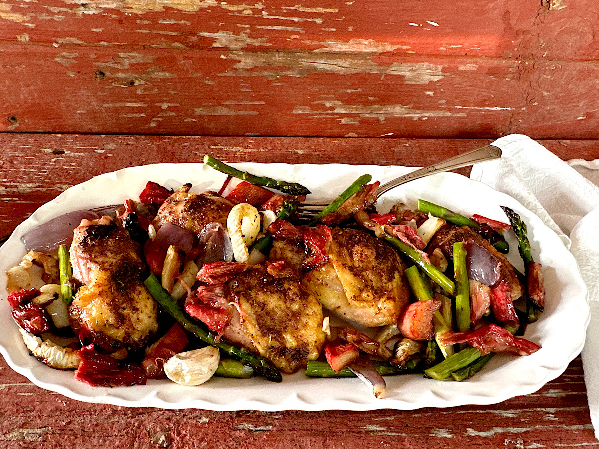 White oval platter with roasted chicken, rhubarb, asparagus and fennel.